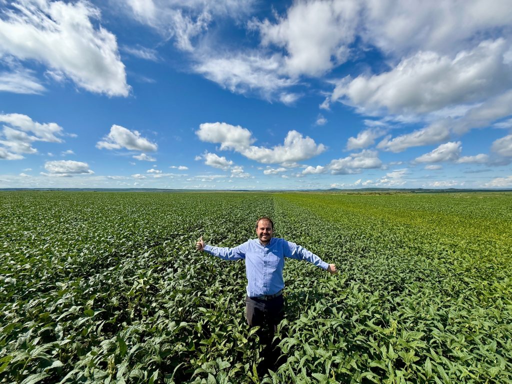 Dr. Eduardo Cancellier showing a field divided between lush, dark green BIOZ® treated plants on the left and paler control plants on the right.
