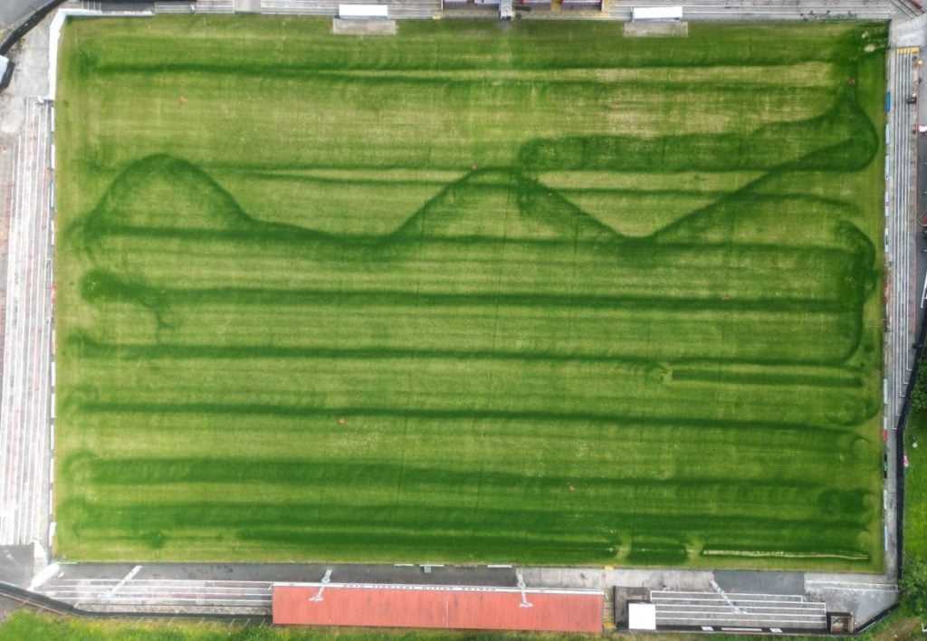 Striature scure e storte su campo di calcio dovute a errori di spargimento del concime a causa di un uso sbagliato dello spandiconcime. Direzione e andatura sono errate