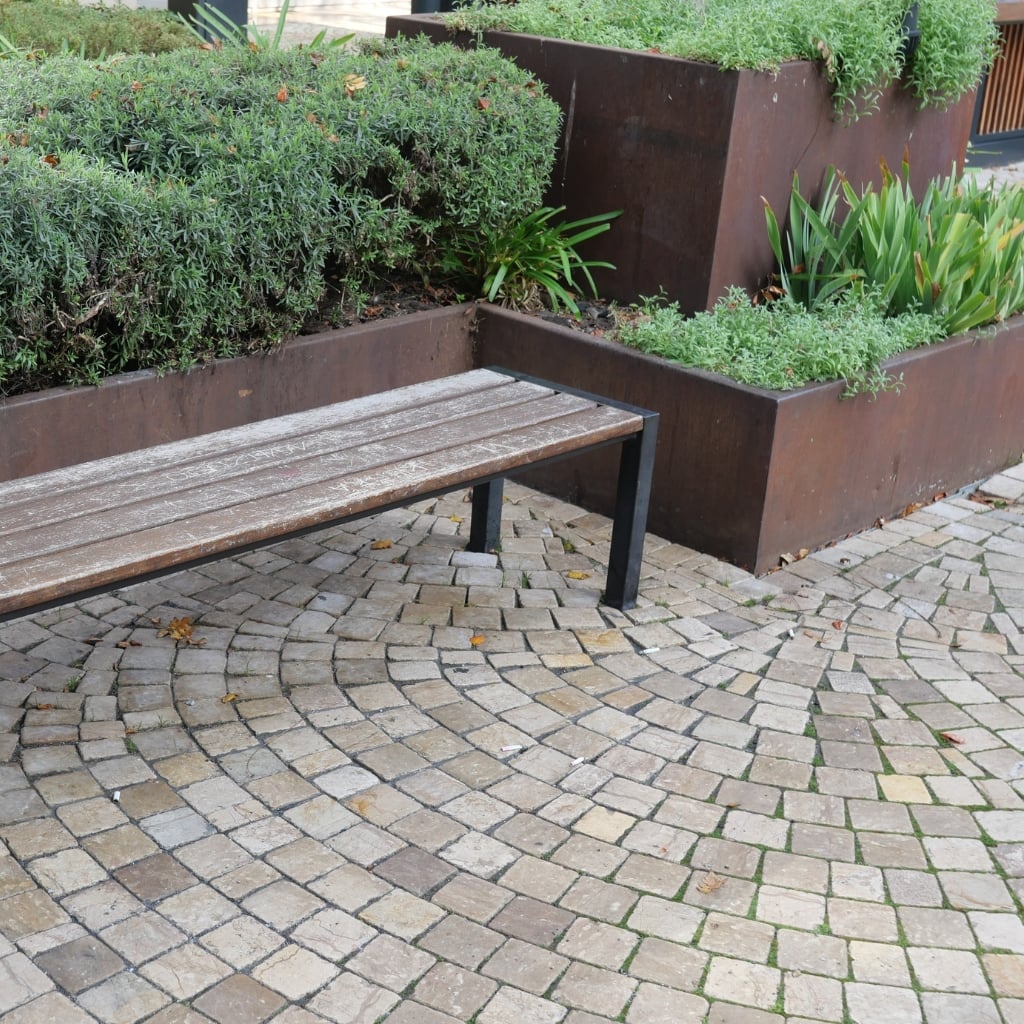 Siepi sempreverdi potate in fioriere decorative per la valorizzazione di aree urbane del verde ornamentale esterne per il pubblico vicino a panchina.